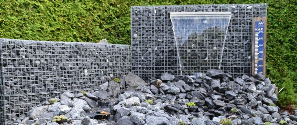 Gabionen-Wasserfall mit kleinem Bachlauf aus grauen Natursteinen und Steinkörben im Garten