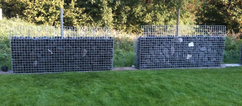 Zwei Gabionen Hochbeete nebeneinander in einem grünen Garten